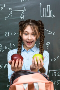 Schoolgirl girl enjoys lunch two ripe apples.