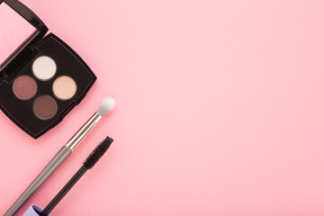Colorful eyeshadow palette, makeup brush and black eyes mascara on light pink table background. Pastel color. Female beauty products. Closeup. Empty place for text. Top down view. - 792819459