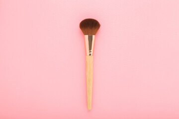 New big makeup brush with soft bristles on light pink table background. Pastel color. Female beauty product. Closeup. Top down view. - 792819469