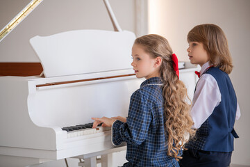 Two children are playing the piano.