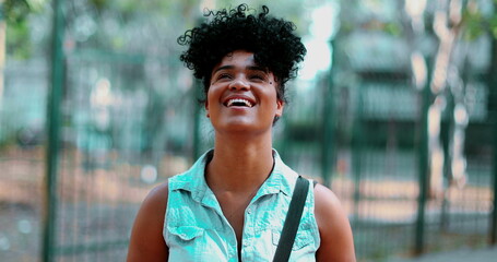 One carefree young black woman looking up at sky smiling feeling joy during sunnny park day...