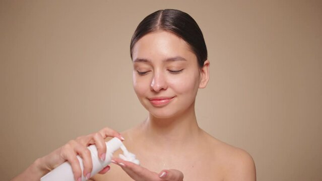Young woman washes face with face wash foam. Daily facial skin care routine. Closeup view, slow motion 4K footage
