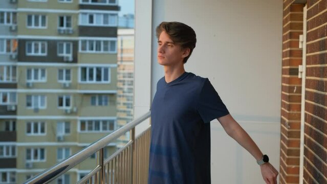 Beginner slim guy athlete doing exercises on the balcony of a multi-story building