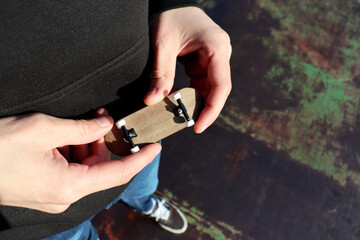 Male hand holding blank wooden fingerboard, close up. Mini skateboard, small skateboard deck © Tom