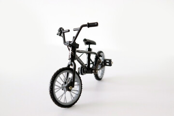 Small black BMX bike miniature toy on white background, close up.