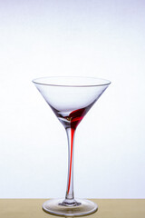 Martini glass on a beautiful long stem with a red accent on a light background