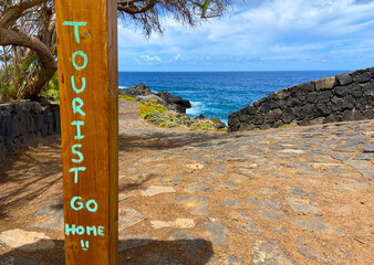 Tourist Go Home graffitti on ocean beach background. Stop mass tourism concept.
Tourismophobia in Tenerife,Canary Islands,Spain.
Selective focus.