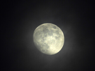 moon in waxing gibbous phase behind misty clouds