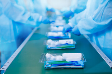 Surgery kit on conveyor line, Precise assembly of medical tools, including scissors, laid out in...