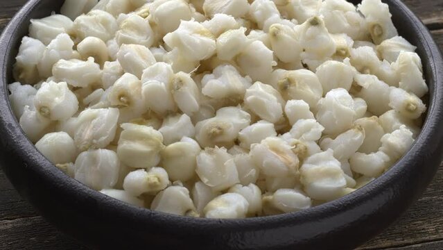Canned white hominy for traditional Mexican pozole in a bowl on a rustic wooden background. Table spin.