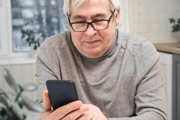 Hoary old man looking at web camera, holding phone, talking with children, wife online. Senior...