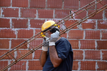 Builder working on construction site. Mason carrying an iron beam. Professional bricklayer working...