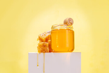 Golden flower honey in a small jar, with honey spoon and honeycomb 