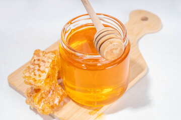 Golden flower honey in a small jar, with honey spoon and honeycomb 
