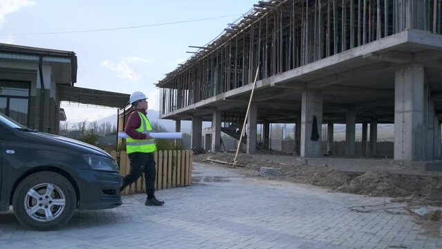 Foreman contractor with blueprints of the building arrived by car to the construction site to get acquainted with the object of the new project.