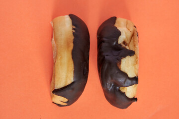 top view of 2 profile of chocolate-covered donuts facing each other, top view on pastel orange background
