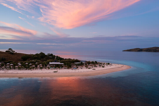 Labuan Bajo, Indonesia: Dramatic aerial view bungalows on an idyllic beach on a small islolated island near Komodo in Flores in Indonesia at sunset