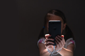 Young girl at night communicates on Internet. Child gadget addiction and insomnia. Anxiety and sleep deprivation as the side effects of internet addiction in children and young people. Copy space.