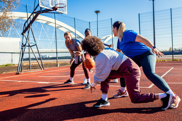 Diverse group of young woman having fun playing recreational basketball outdoors.