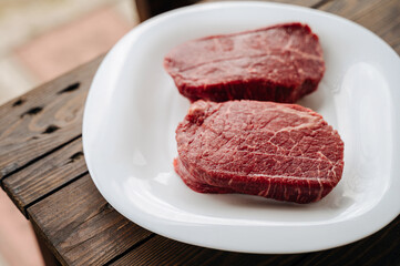 raw juicy piece of steak on a white plate