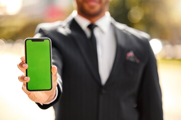 Hand, show and outdoor with phone, green screen and person in corporate, business and advertising. Mobile, display and technology of product placement, suit and bokeh in city, park and New York