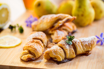 Sweet pastries, puff pastries with pears, on a wooden table