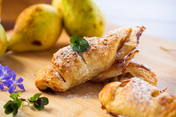 Sweet pastries, puff pastries with pears, on a wooden table