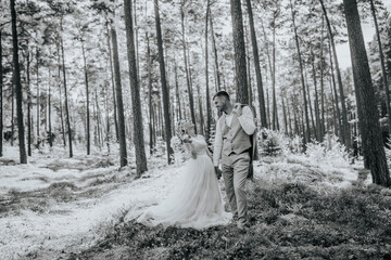 Valmiera, Latvia - August 10, 2023 - Wedding couple in a forest, with the bride looking at the groom and touching his face.