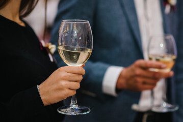 Tasting white wine. Couple drinking wine closeup. Beautiful girl and man holding glass of wine indoors. People hands hold glass of champagne. Friends and summer concept.