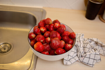 plate with fresh strawberries on the kitchen counter
