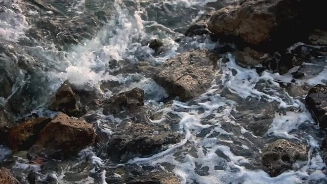 Slow Motion, close up: swells hits the rocks at sunset in Ceuta, Spain