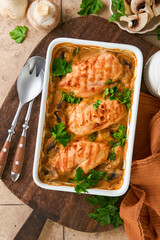 Baked chicken breast bbq with mushrooms and garlic in cream sauce on old brown concrete tilestable backgrounds. Top view image with ingredients for cooking. Top view with copy space.