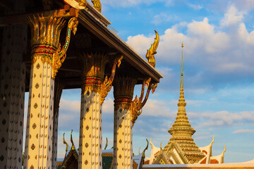 View on decorated pillars of the Ubosot or Ordination Hall from Wat Arun against great blue sky at...