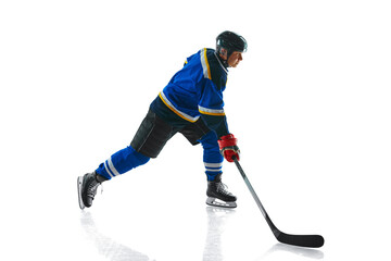 Hockey athlete, skater in gear maneuvers puck in motion against white studio background. Dynamic...
