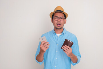 A man showing confused expression while holding mobile phone and wallet