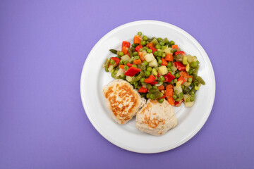 Roasted chicken cutlets with vegetables on white plate