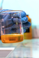A person is holding a beaker with a yellow liquid in it