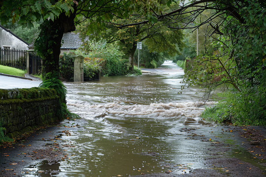 Fototapeta Torrential rain causes a river to overflow - flooding nearby paths and causing disruption in the lives of local residents