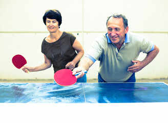 Happy mature spousesn playing table tennis