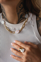 Young woman with a tattoo shows off jewelry on her neck and arm - a necklace with freshwater pearls...