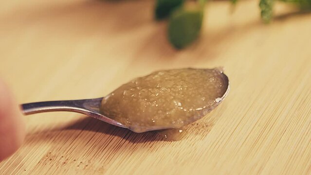 Woman holding spoon full of fresh unprocessed natural honey on a wooden table in the kitchen. Indoor. Studio. Close up. High quality 4k footage