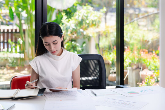 Young businesswoman working with documents in office. Businesswoman holding papers preparing report analyzing work results.