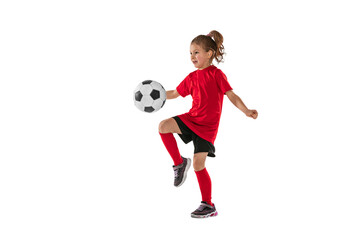 Portrait of girl, child, football player in red uniform training, kicking ball with knee against transparent background. Sportive and active kid. Concept of action, team sport game, energy, vitality.