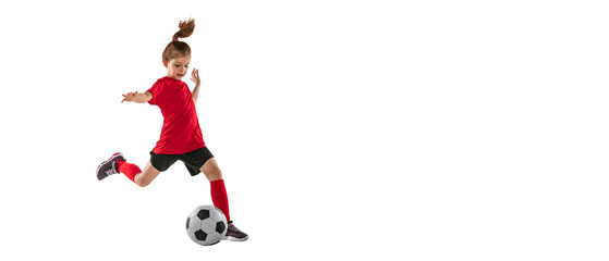 Portrait of athletic, fit child, girl in red uniform playing, training pass technique against transparent background. Sportive and active kid. Concept of action, team sport game, energy, vitality.
