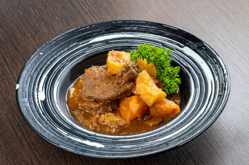 A plate of beef stew with potatoes and carrots