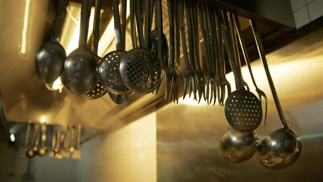 Ladles And Skimmers Hanging On The Hood Of A Restaurant Kitchen