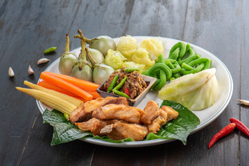 A plate of fried fish with various vegetables and a spicy sauce.