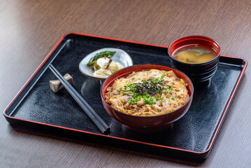 A delicious Japanese dish with rice, egg, and other toppings, served with miso soup and pickles.