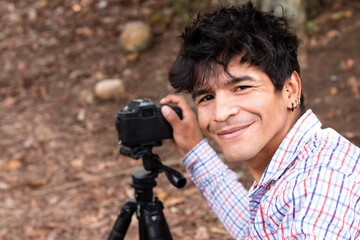 outdoor lifestyle concept. Young Latino man using camera on tripod. smiling look