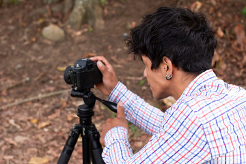 outdoor lifestyle concept. Young Latino man using camera on tripod